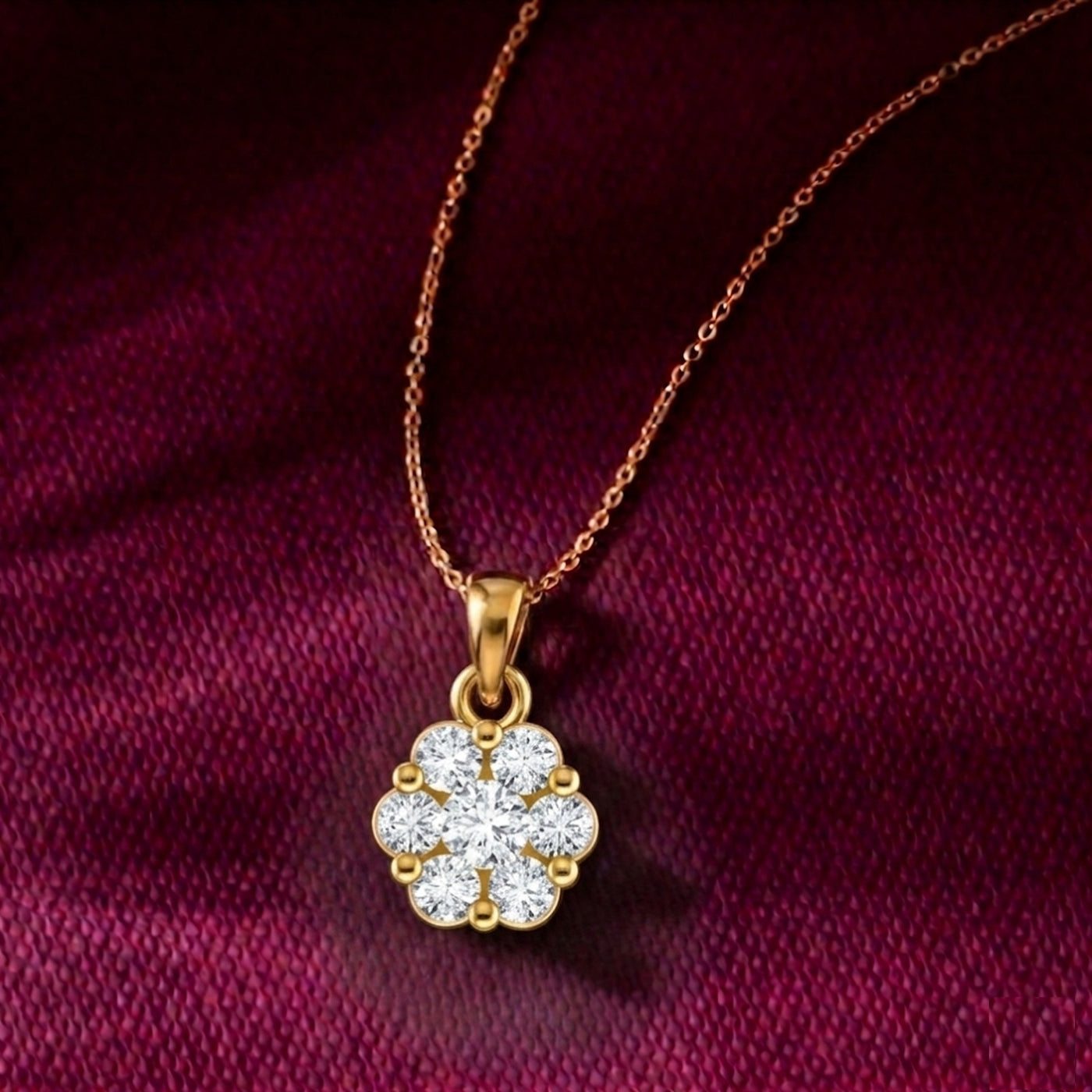 Gold necklace with a clover-shaped pendant on a maroon fabric background