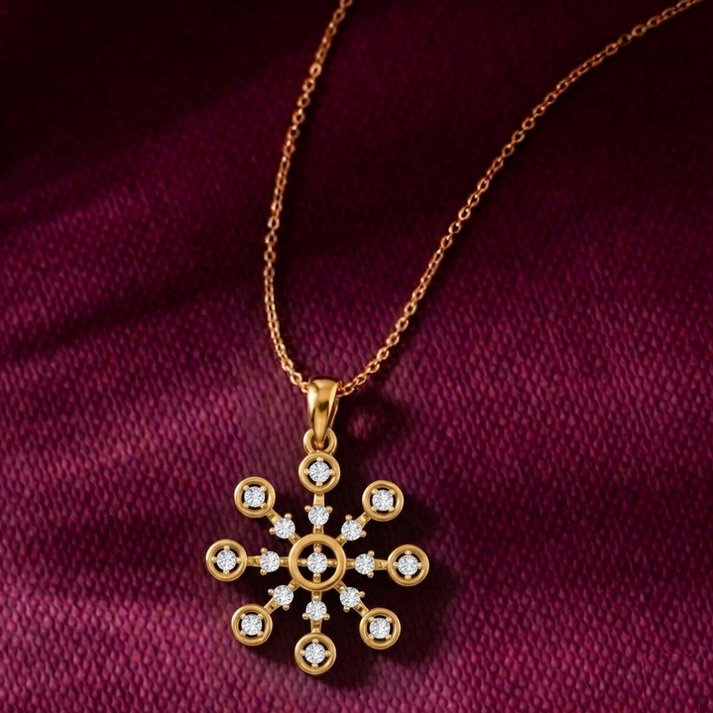 Gold snowflake pendant necklace on a maroon fabric background