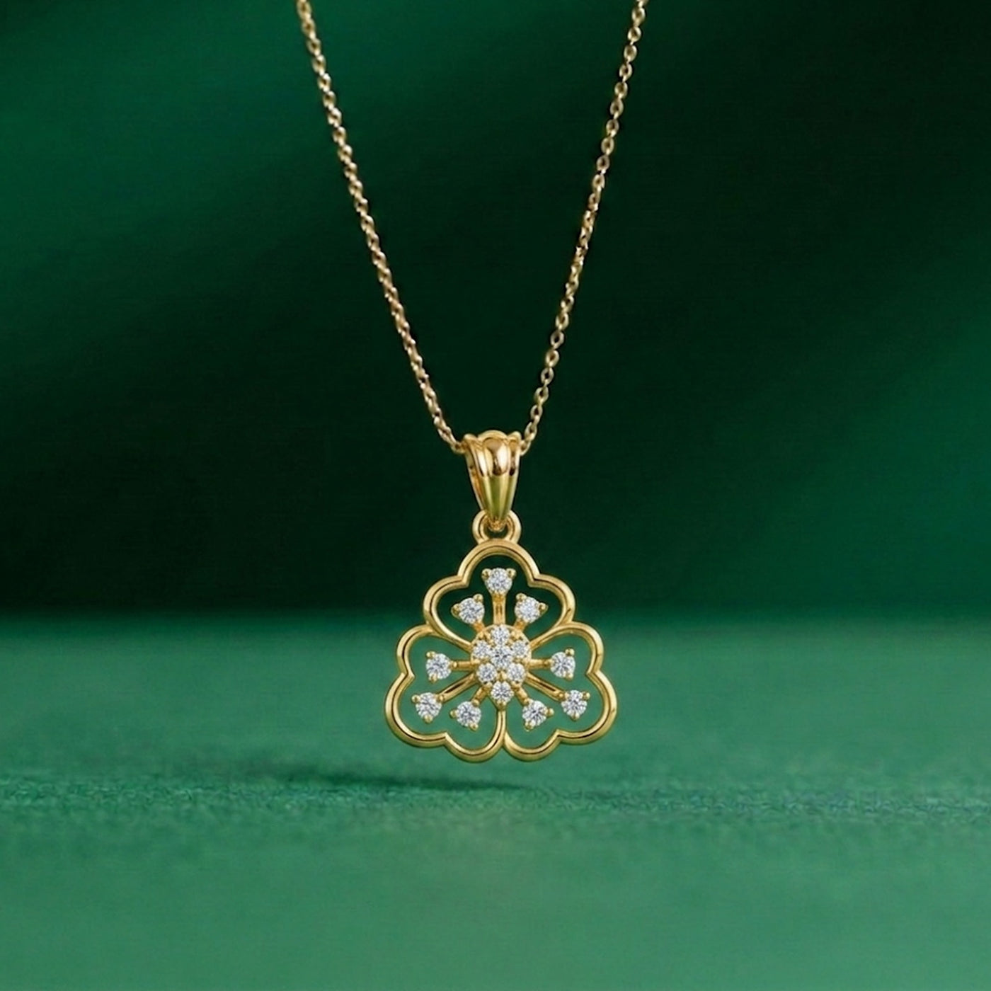 Gold necklace with a floral pendant on a green background