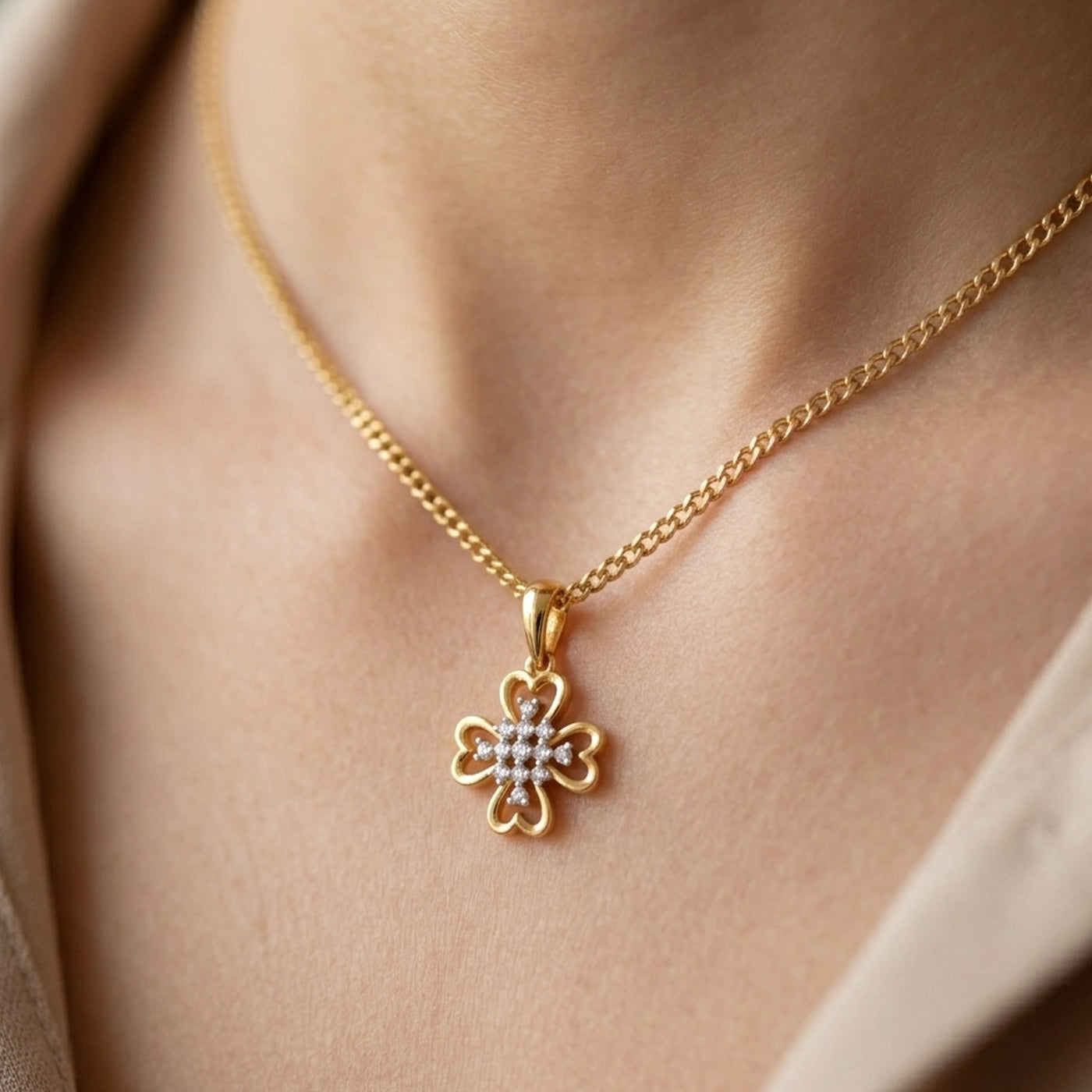 Gold necklace with a clover-shaped pendant on a person's neck
