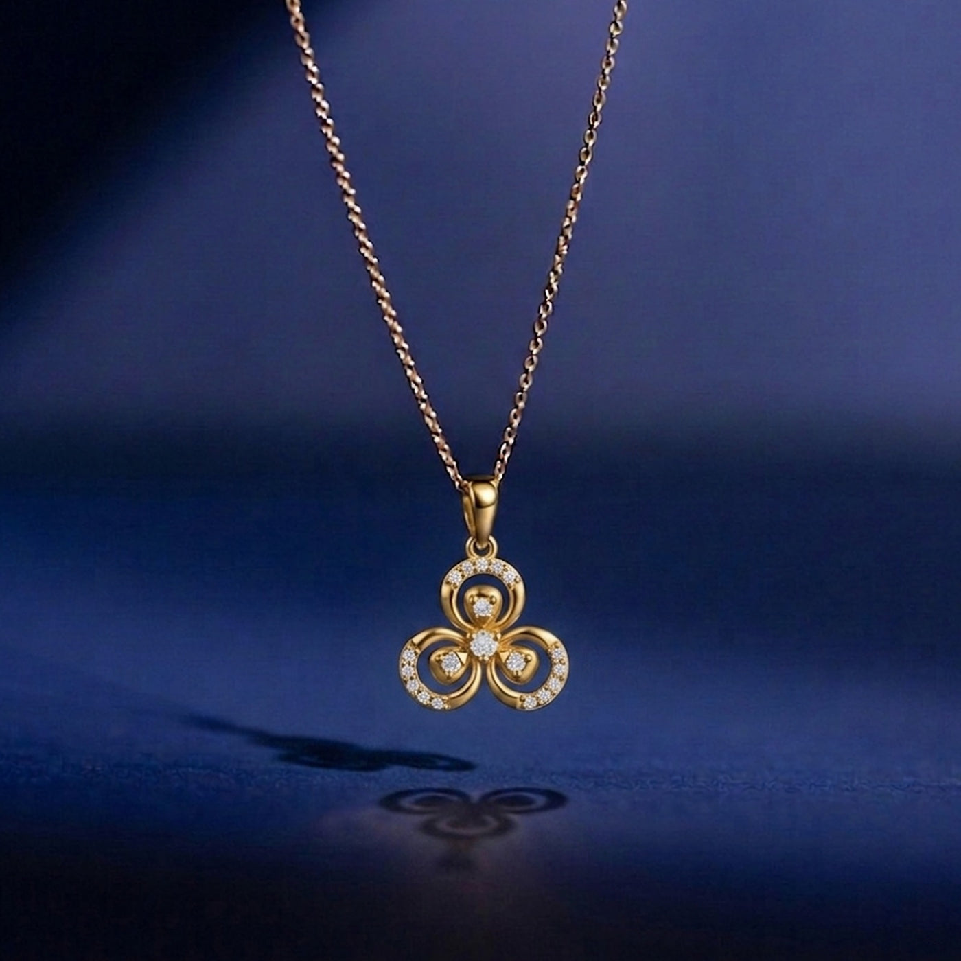 Gold necklace with a trefoil pendant on a dark blue background