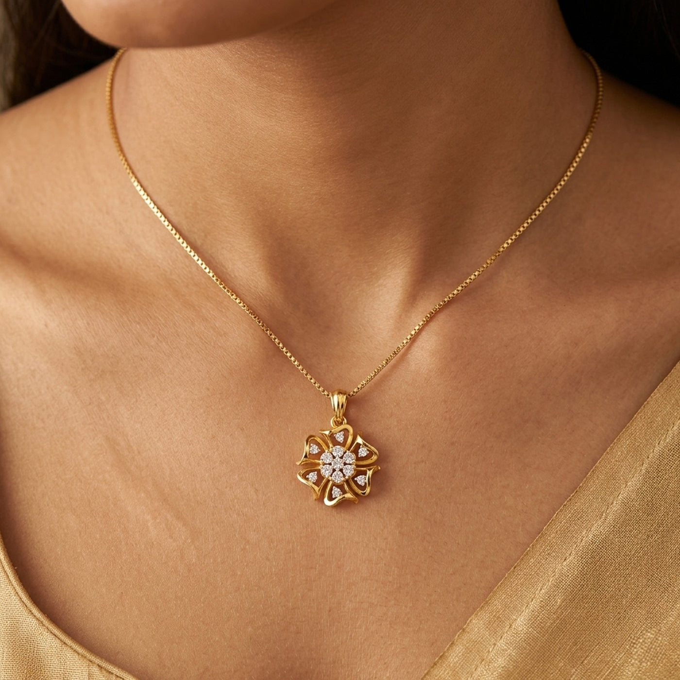 Gold necklace with a diamond pendant on a person wearing a gold top.