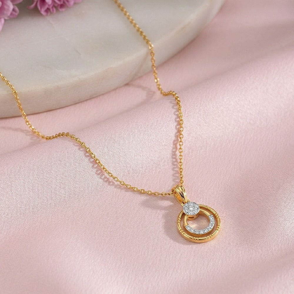 Gold necklace with a circular pendant on a pink fabric background