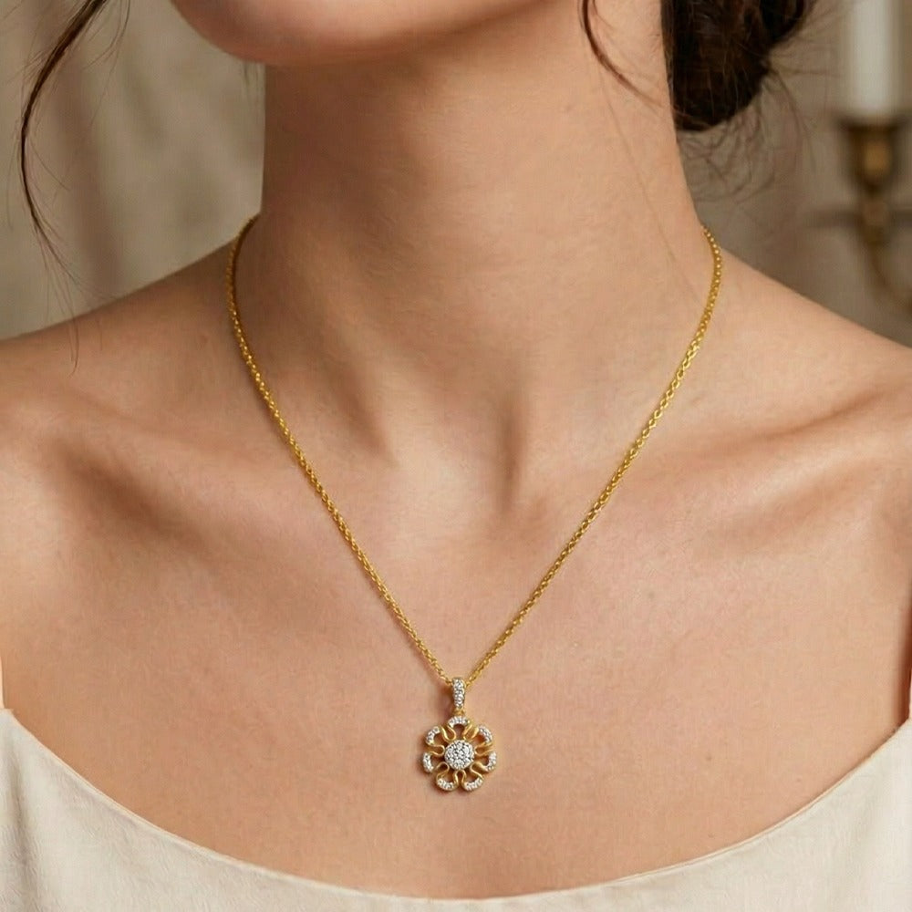 Gold with a floral pendant on a person wearing a beige top.