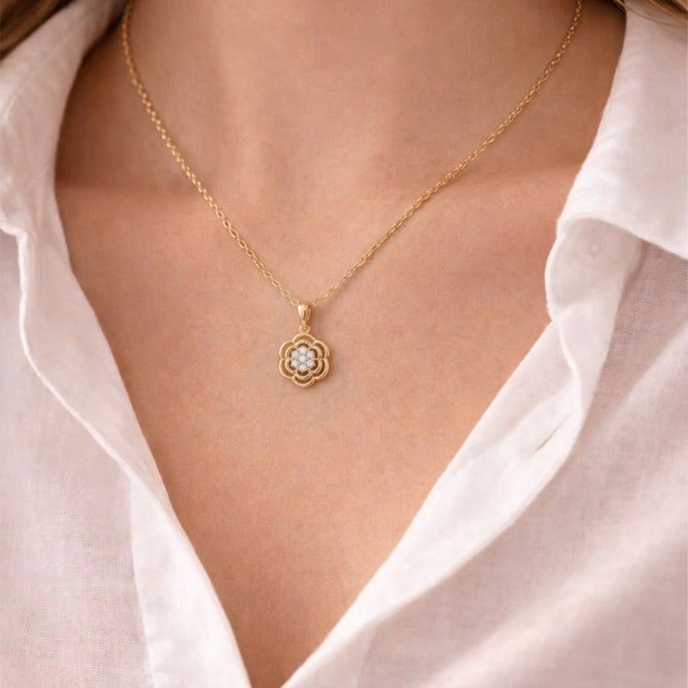 Gold and diamond pendant worn by a person wearing a white shirt.