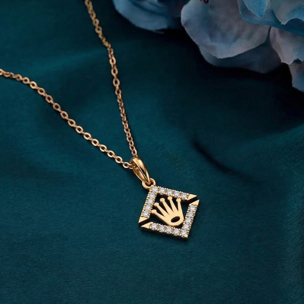 Gold and diamond pendant featuring a hand design on a dark blue fabric background.