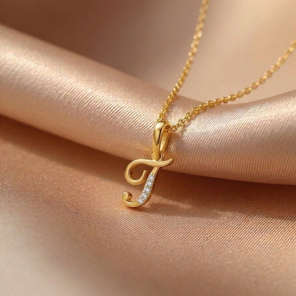 Gold necklace with a 'T' pendant on a beige fabric background