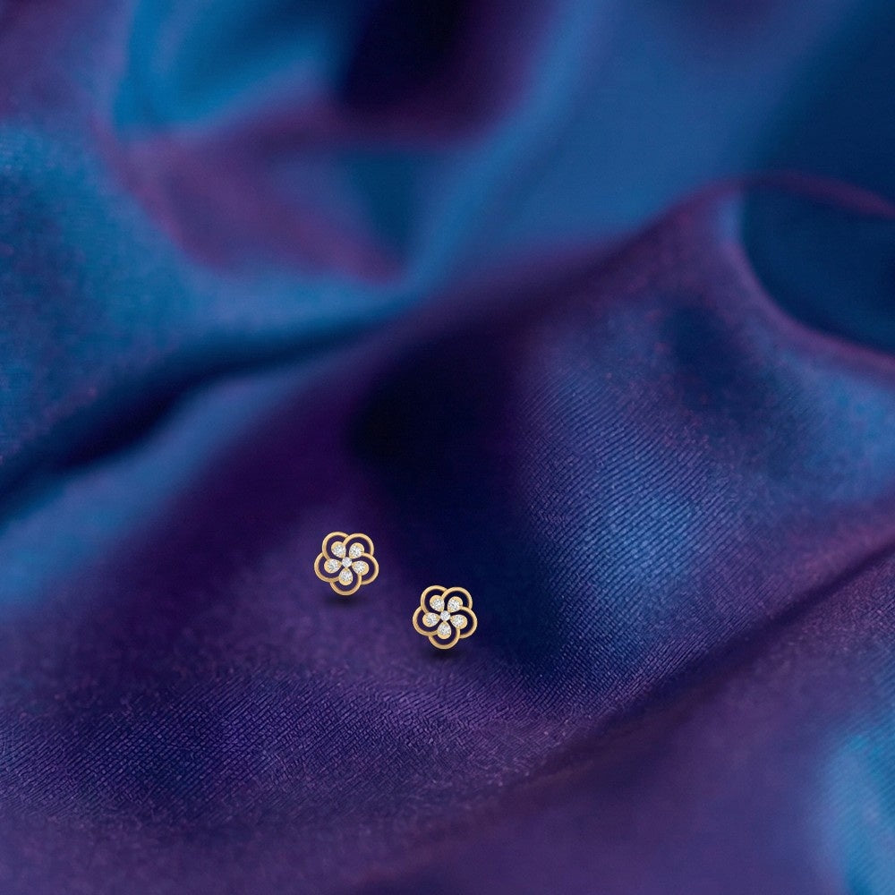 Gold and diamond floral earrings on a blue fabric background