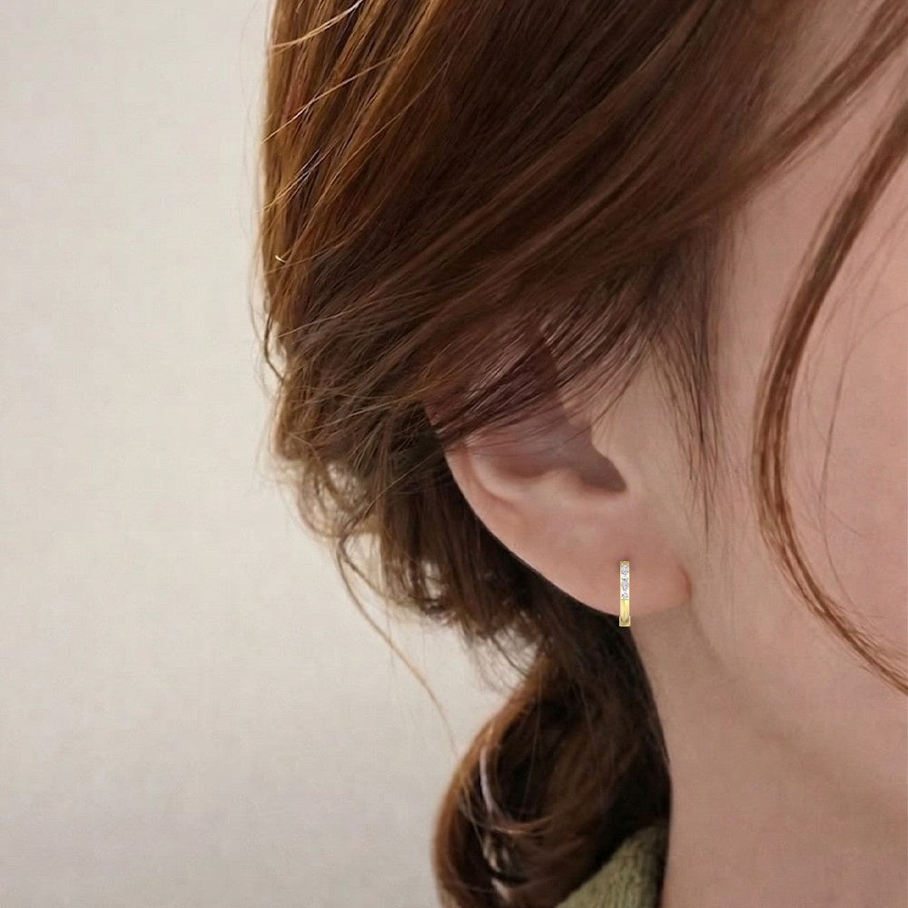 Close-up shot of a gold and diamond hoop earring.