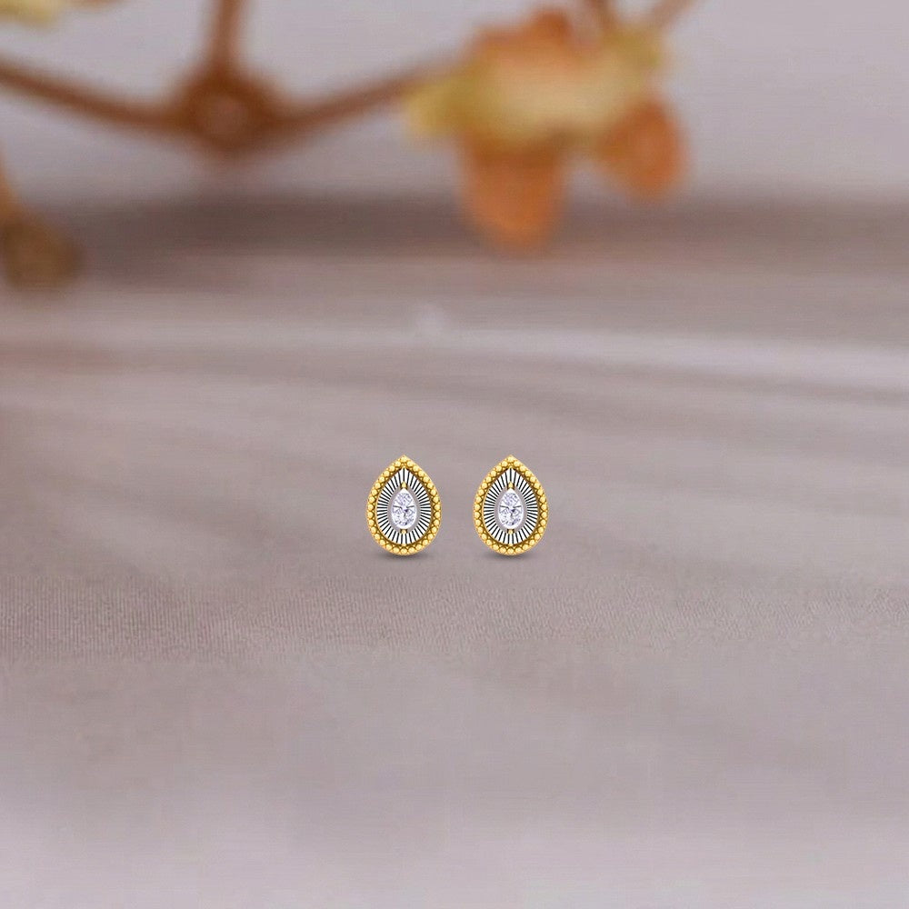 Gold and diamond teardrop-shaped stud earring on a surface.