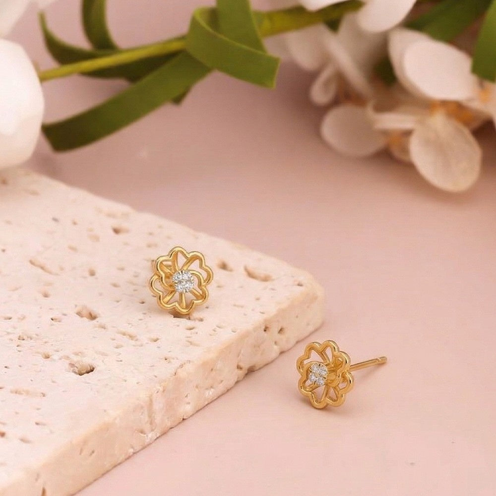 Gold and diamond floral stud earring on a pink background.