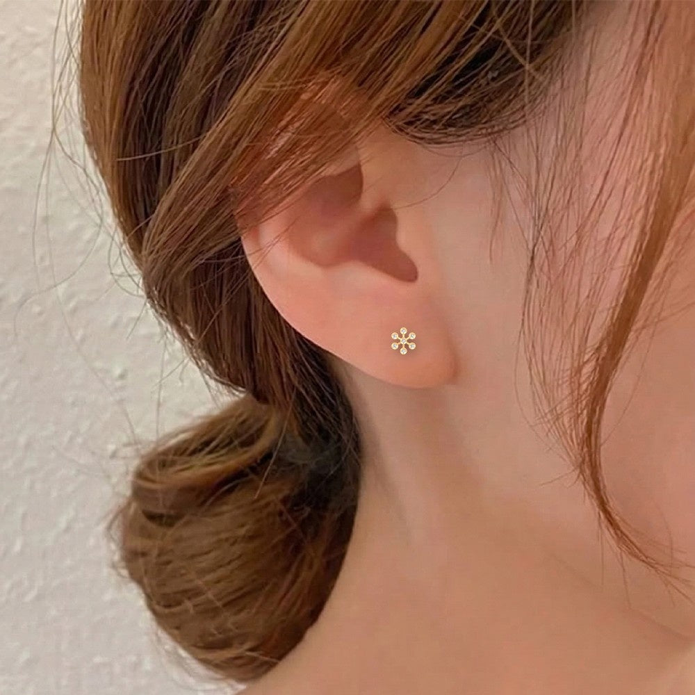 Close-up of a gold and diamond floral stud earring.