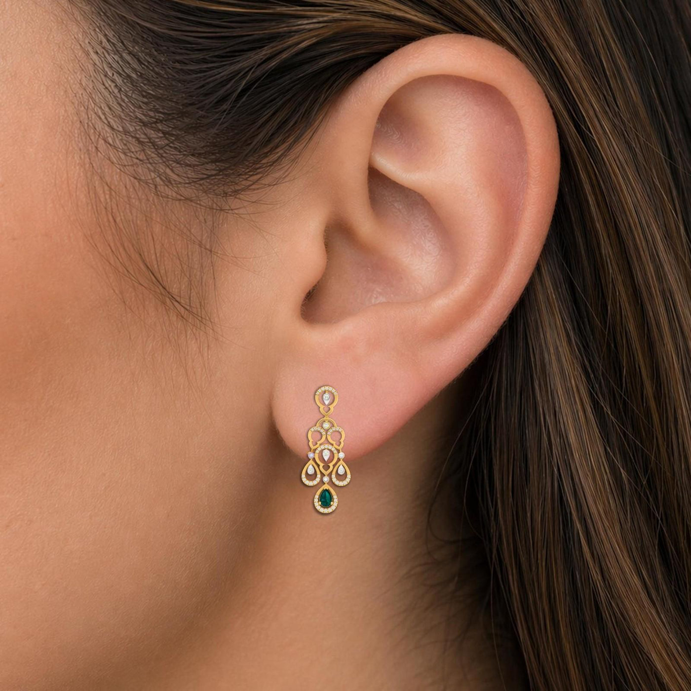 Close-up shot of a gold and diamond teardrop-shaped earrings with clear gemstones.