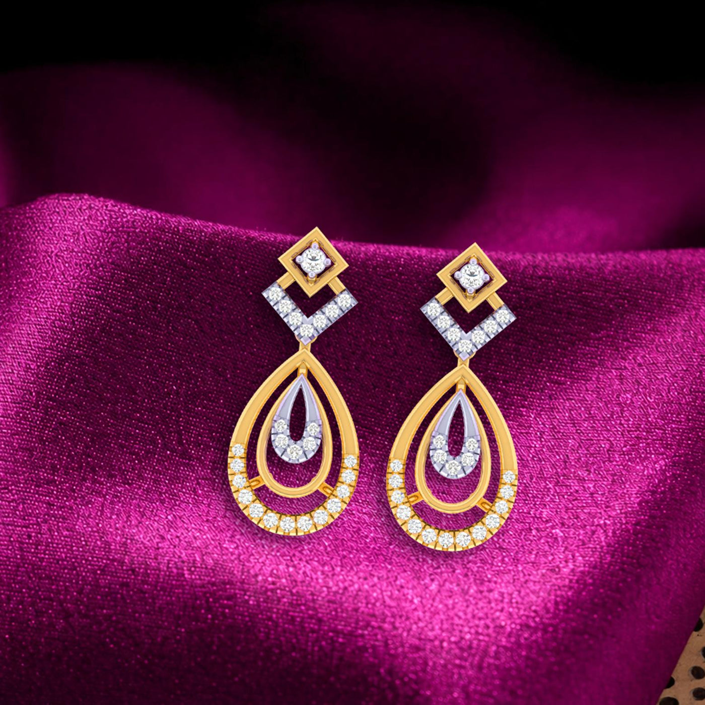 Gold and diamond drop earring with teardrop-shaped on a magenta fabric background.