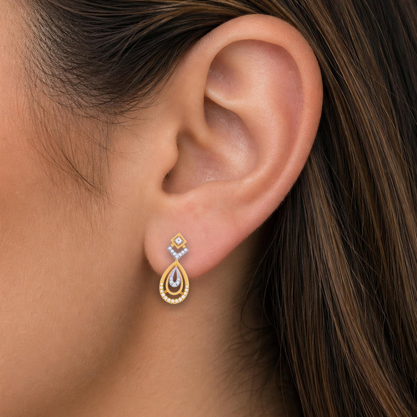 Close-up shot of a gold and diamond drop earring with teardrop-shaped.