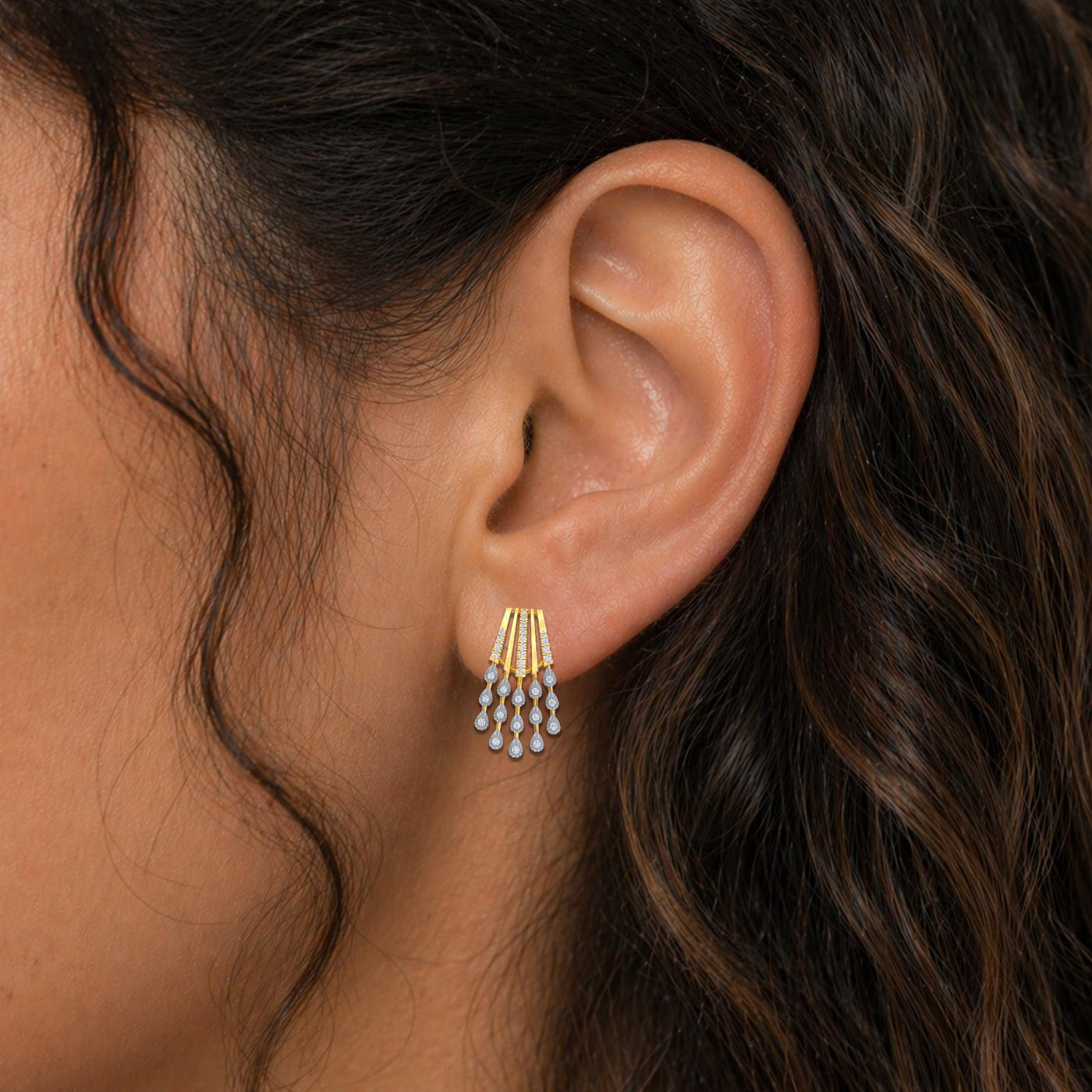 Close-up shot of a gold earrings with multiple teardrop-shaped diamond earring.