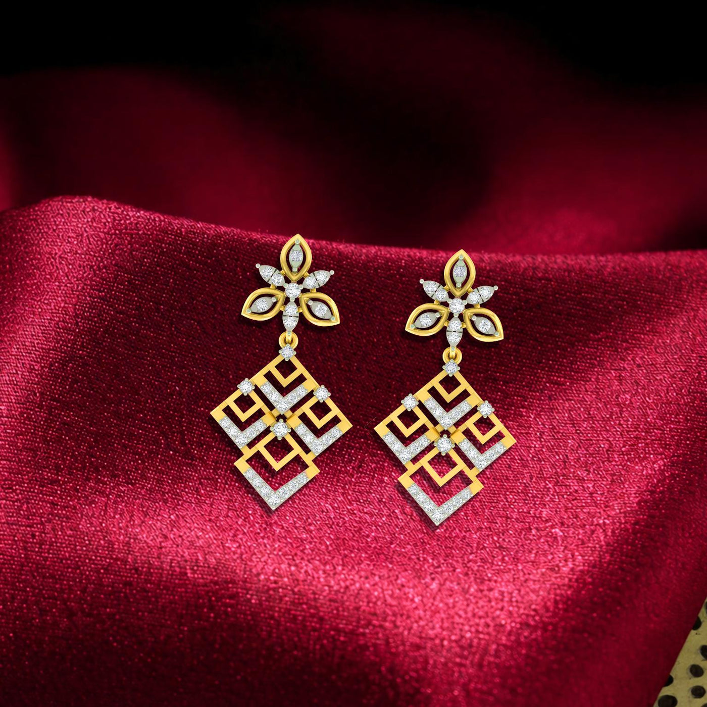 Gold & diamond geometric floral women dangler earrings with openwork diamond design on a red fabric background.