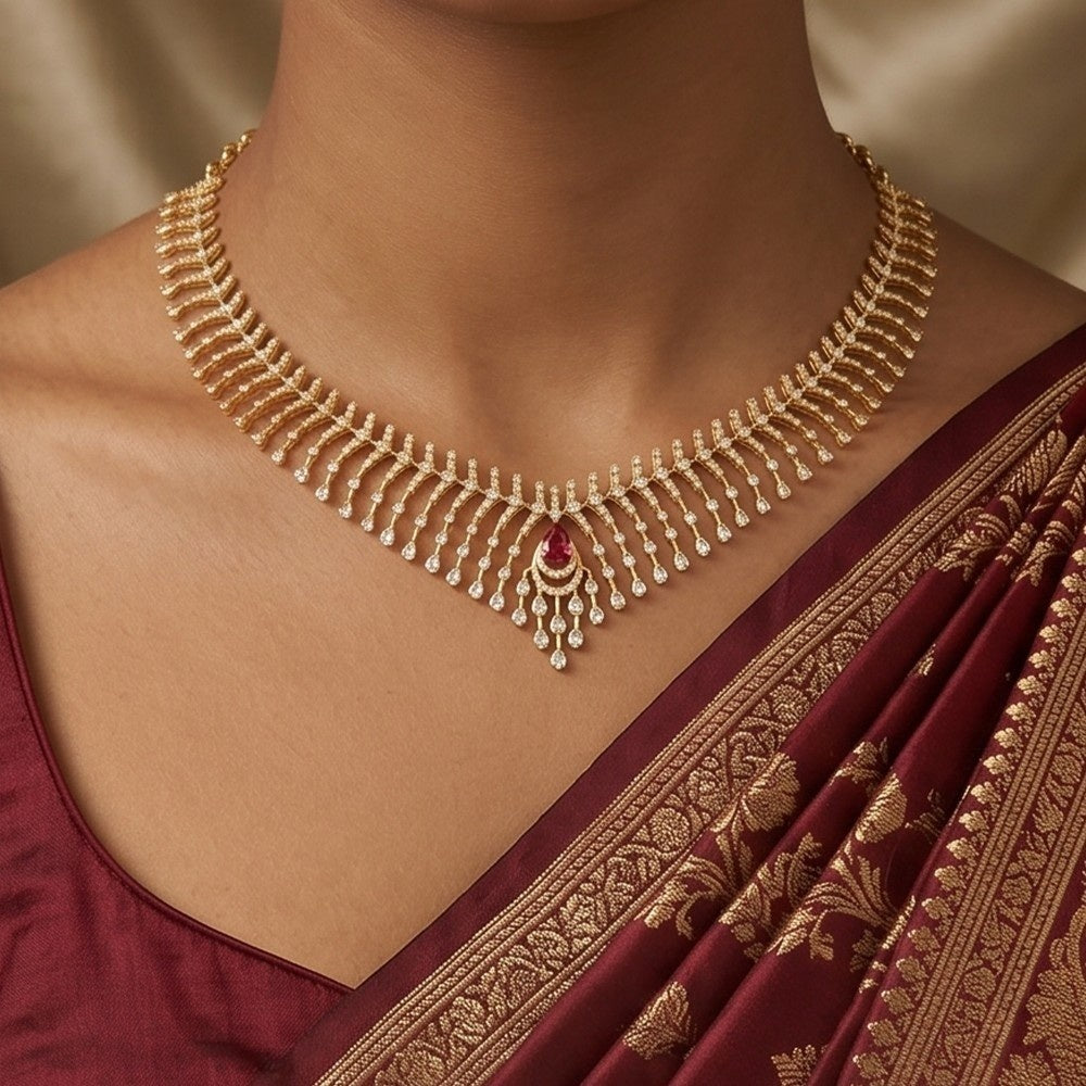 Gold and diamond necklace with a central ruby gemstone, worn on a model's neck over a deep maroon.