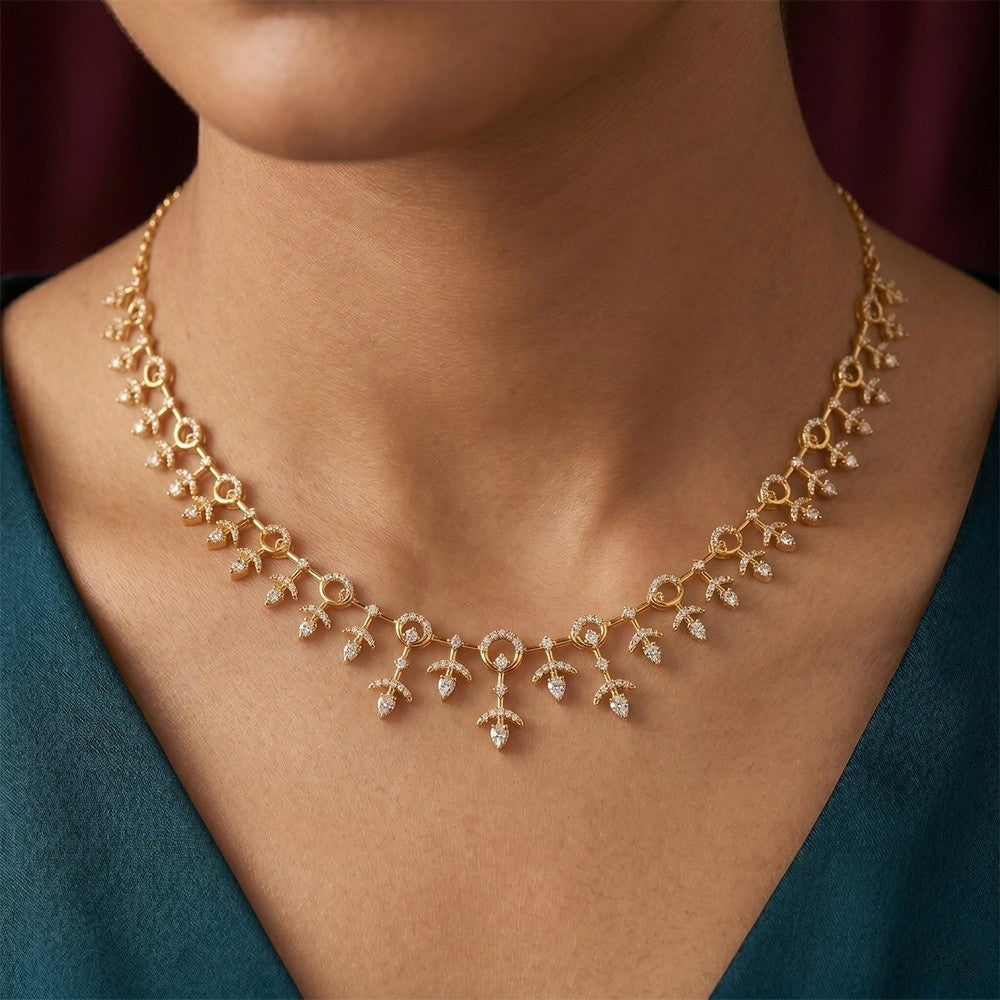 Gold necklace with small diamonds on a person wearing a teal top.