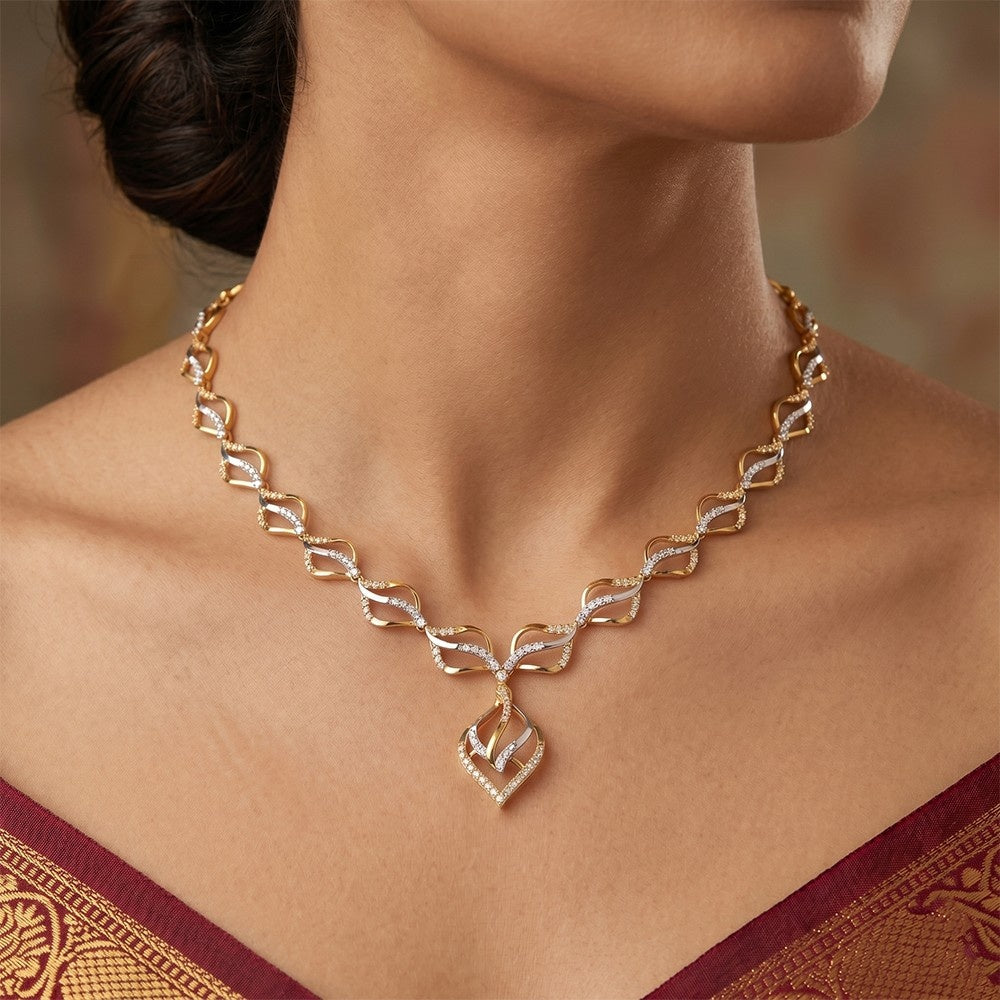 Gold necklace with a heart design worn by a model against a blurred background
