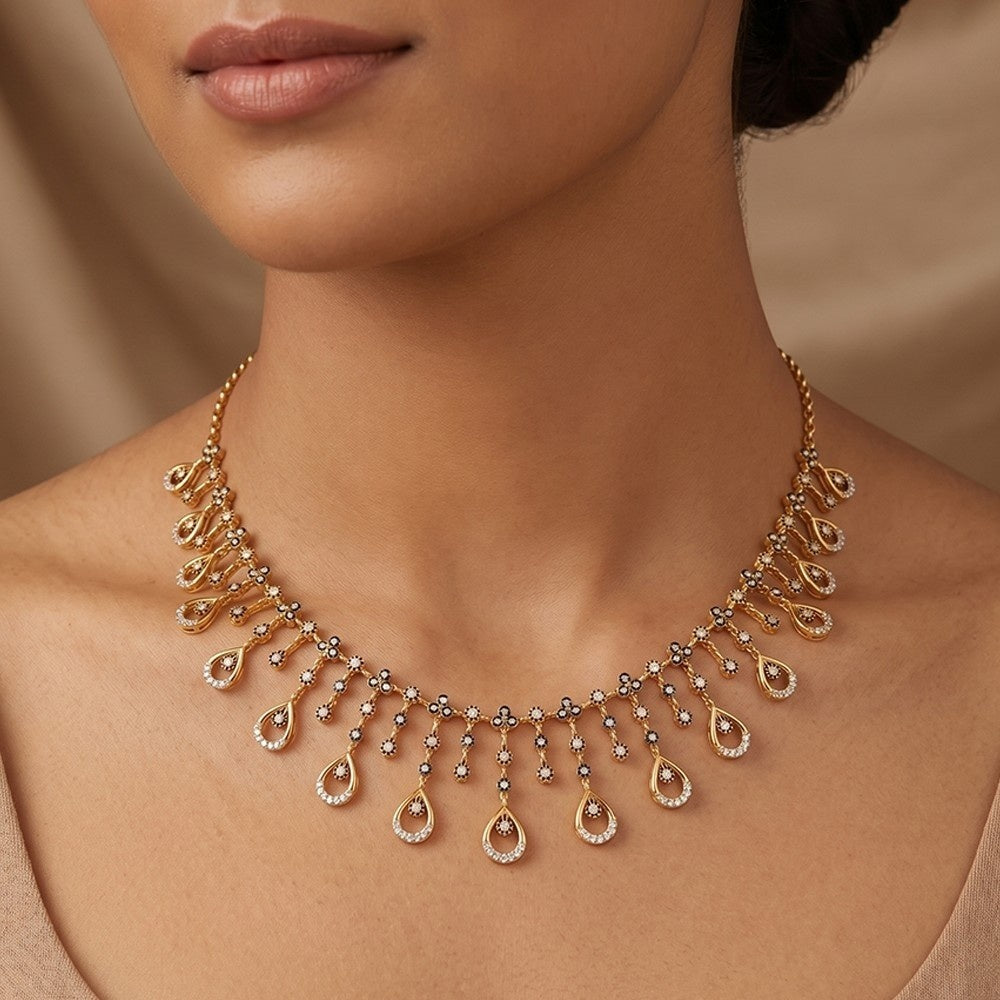 A close-up of a woman wearing a gold teardrop necklace, shown against a soft beige background.