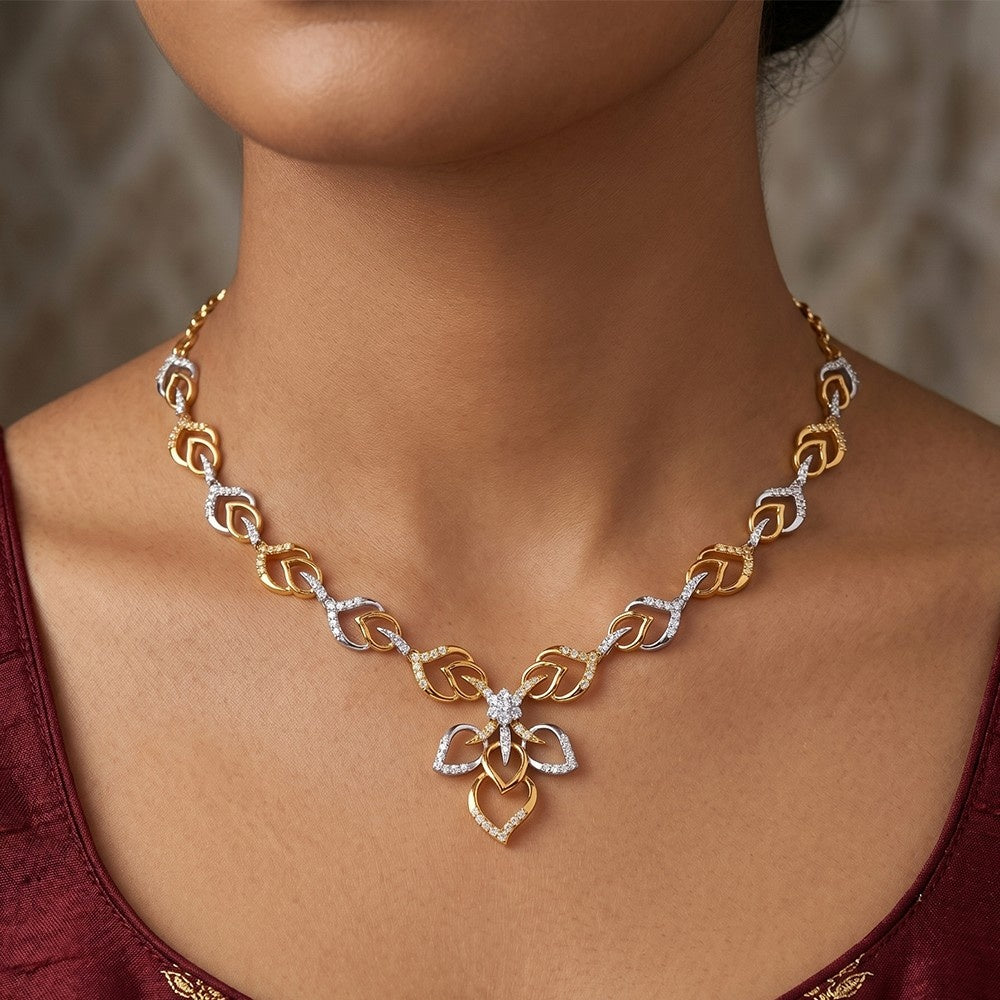 Gold and diamond necklace with a floral design on a person wearing a red top.