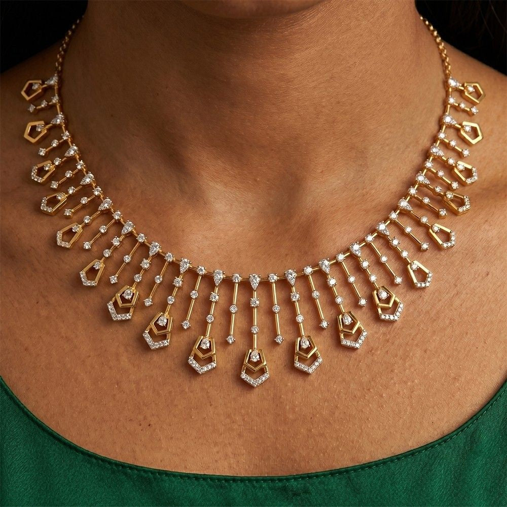 Gold necklace with diamond pendants on a person wearing a green outfit.