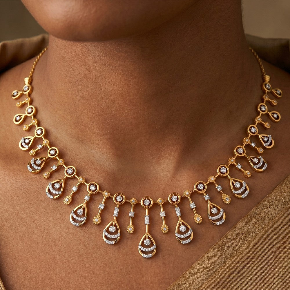 A gold-toned statement necklace with teardrop-shaped drops set with clear gemstones, shown worn on a model's neck.