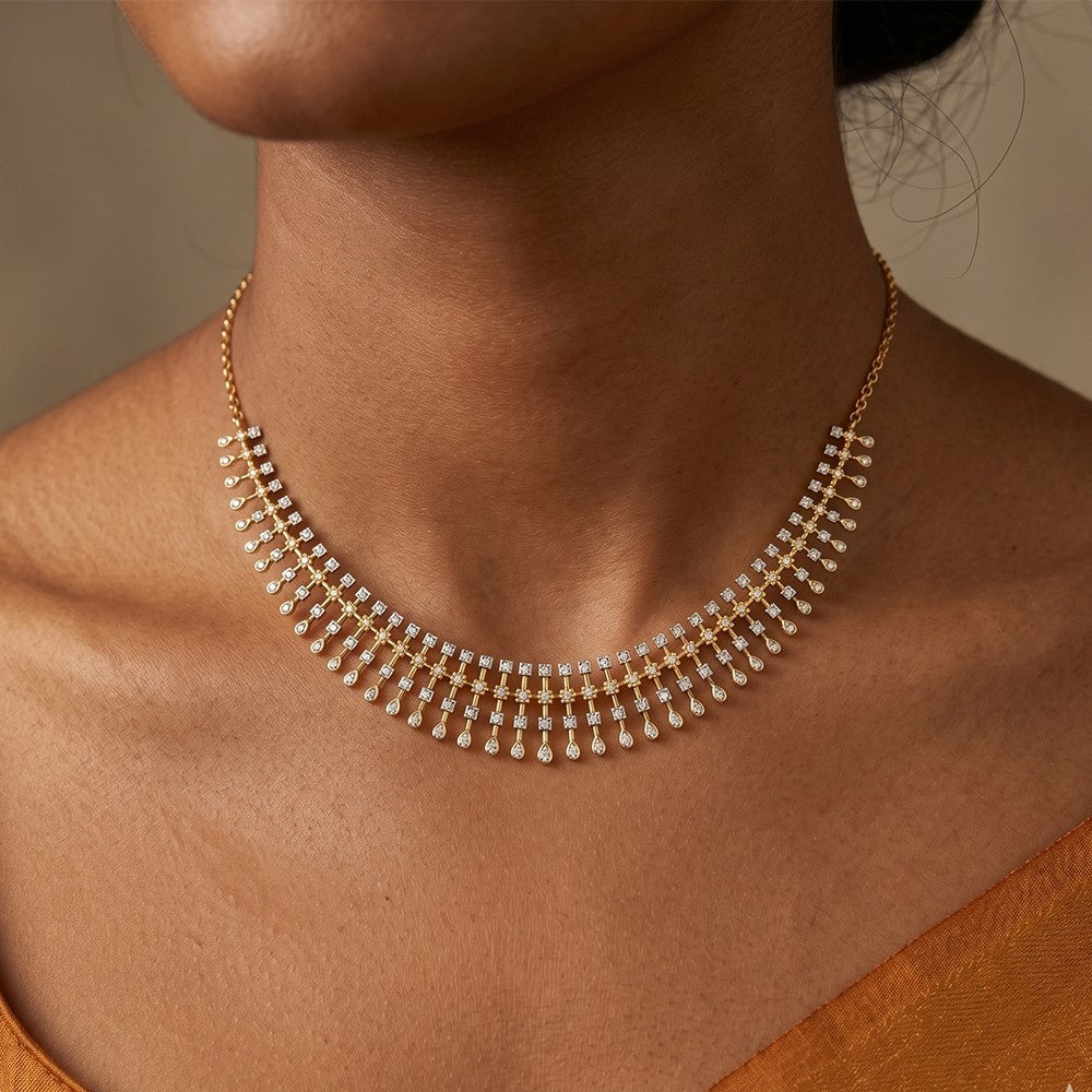 A gold-toned choker necklace with rows of small clear stones and dangling pearl-like drops, shown worn on a model's neck and upper chest.