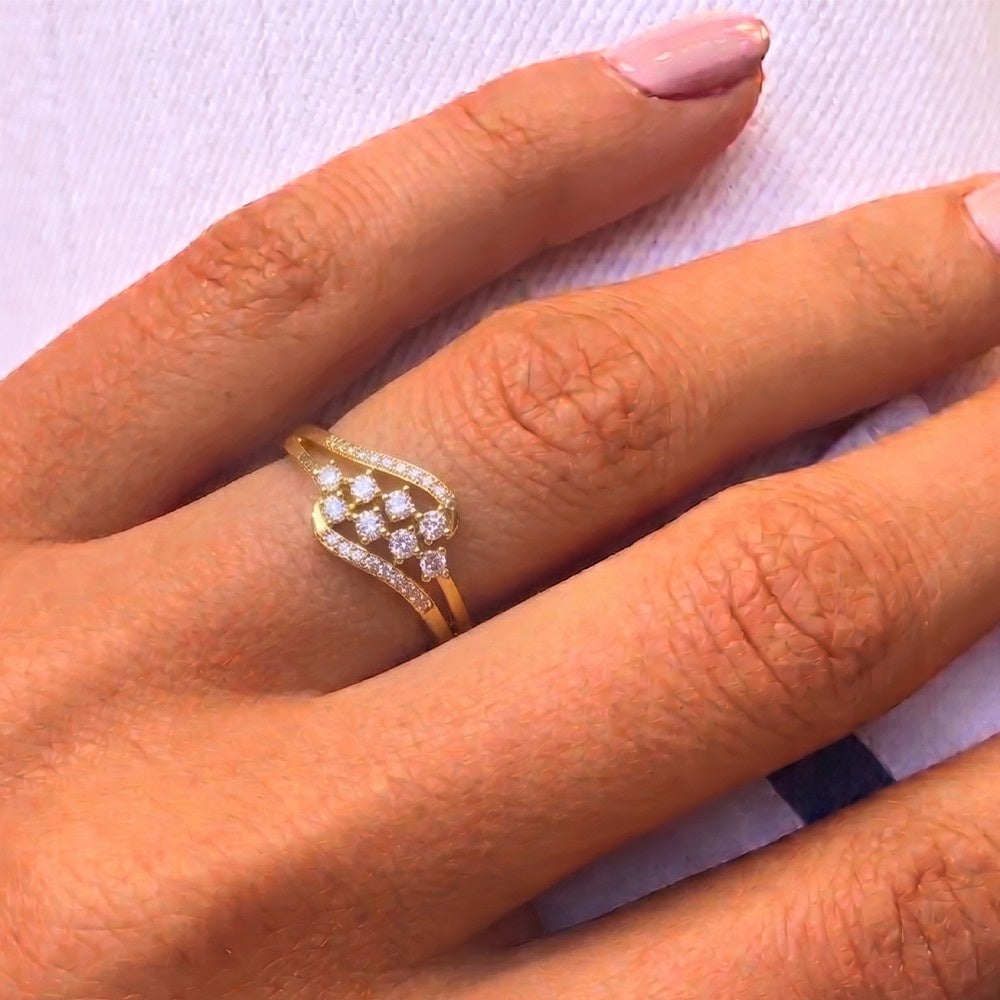 Gold ring with diamonds on a person's finger against a white background