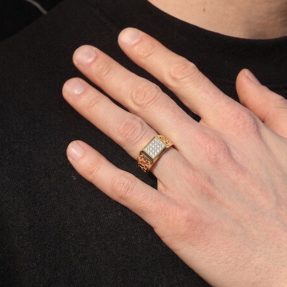 Hand wearing a gold ring with a diamond center on a black background.