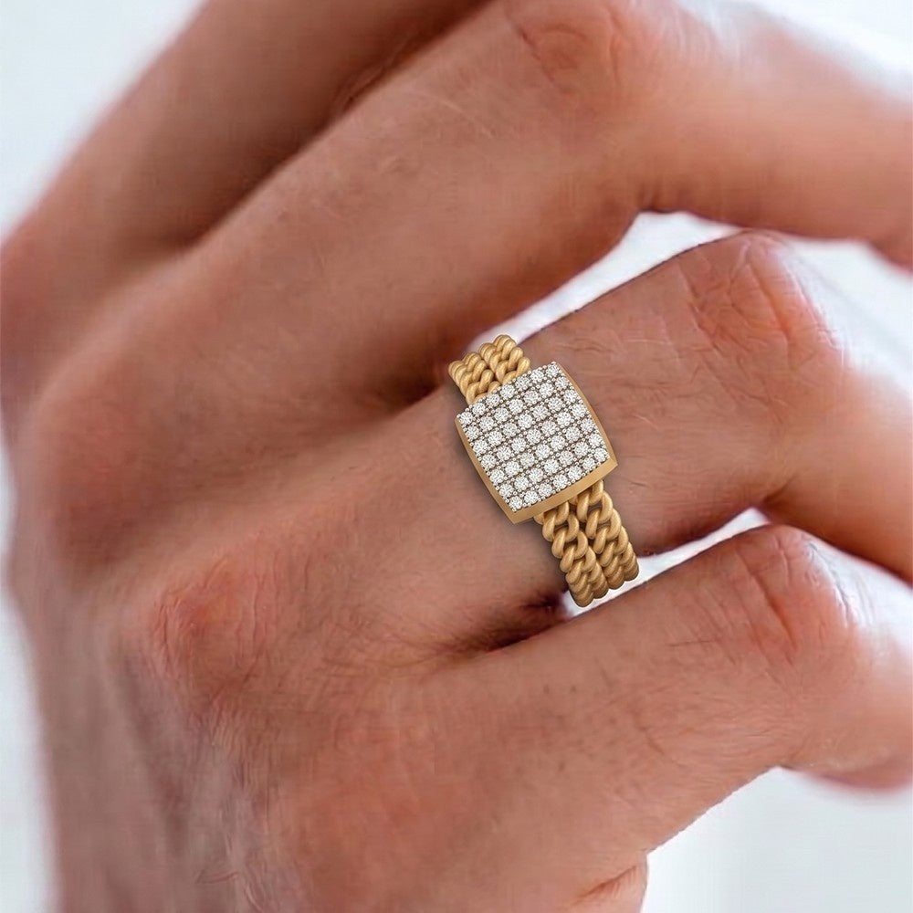 A gold ring with a square face paved, shown worn on a person's finger.