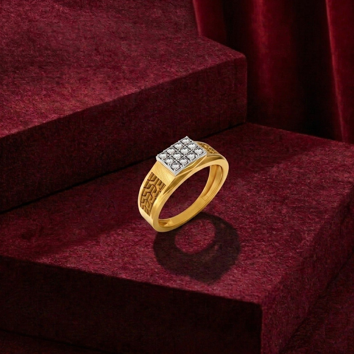 A gold signet ring with a square diamond cluster, displayed on a dark red velvet jewelry box.