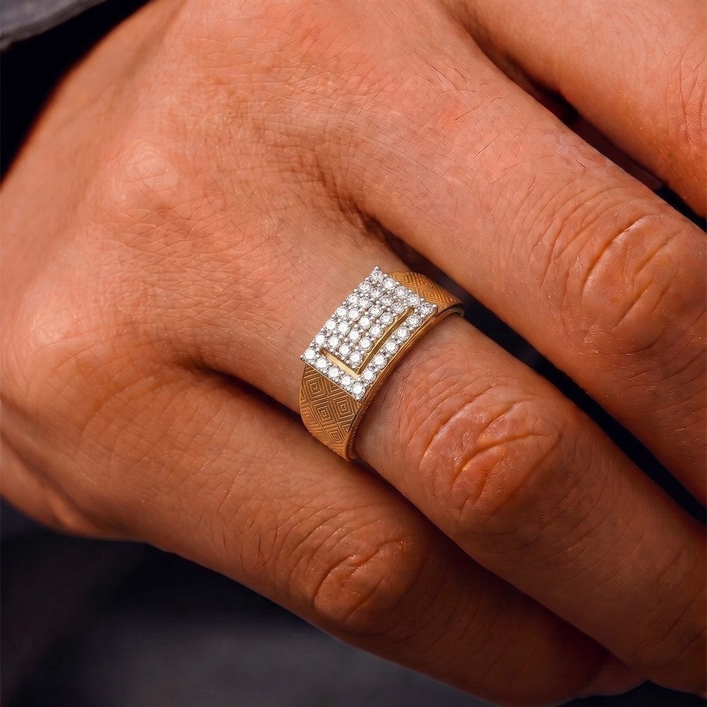A close-up of a gold ring with a square pavé diamond face and a textured band, worn on a person's finger.