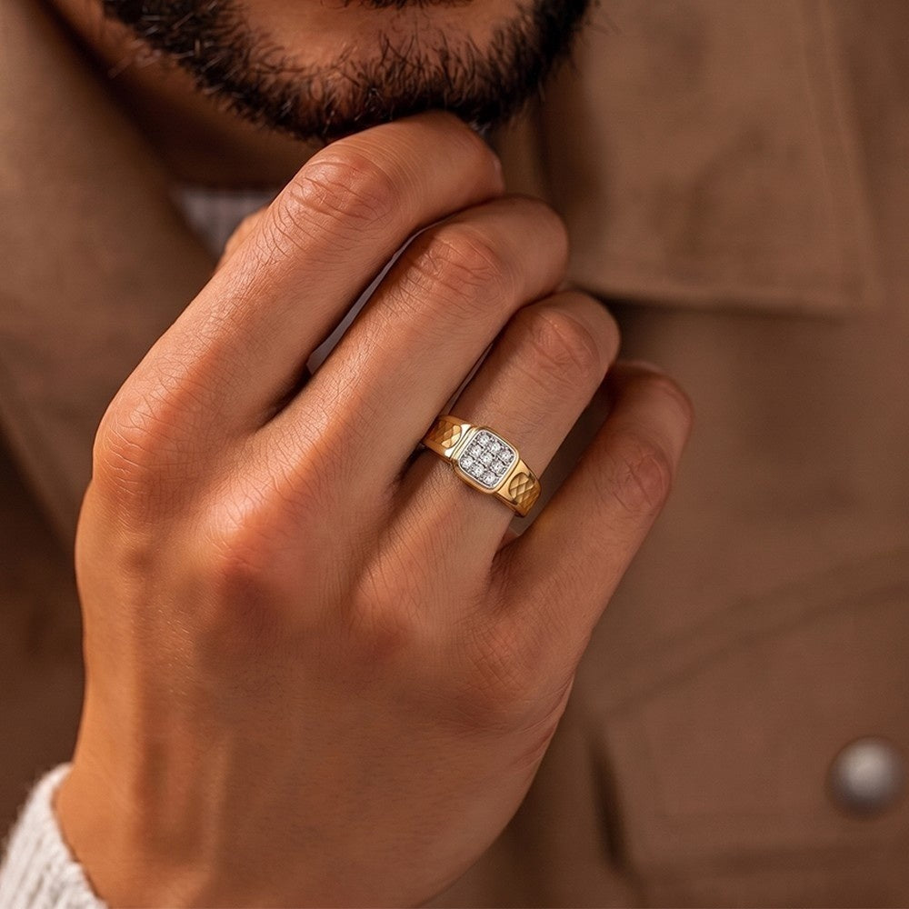 Hand wearing a gold ring with a diamond, against a brown background