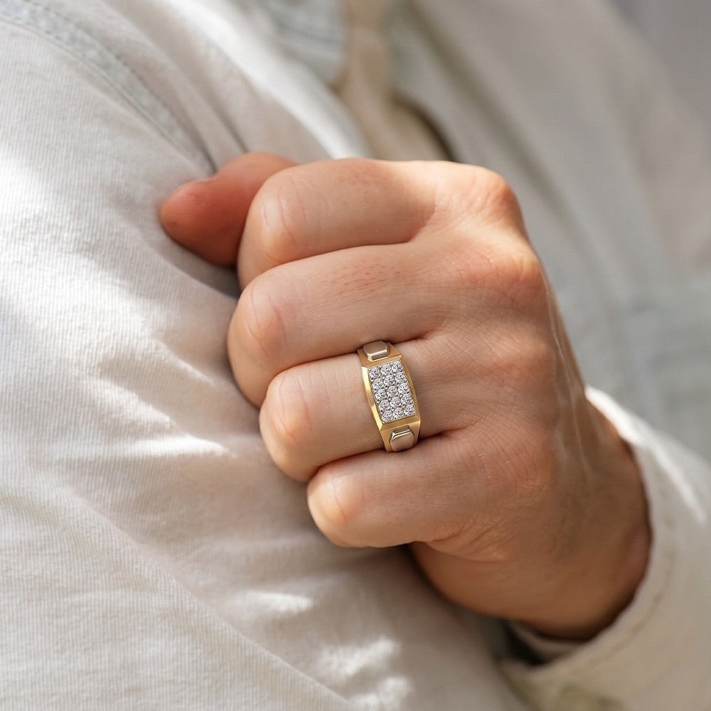 Hand wearing a gold ring with diamonds on a light background