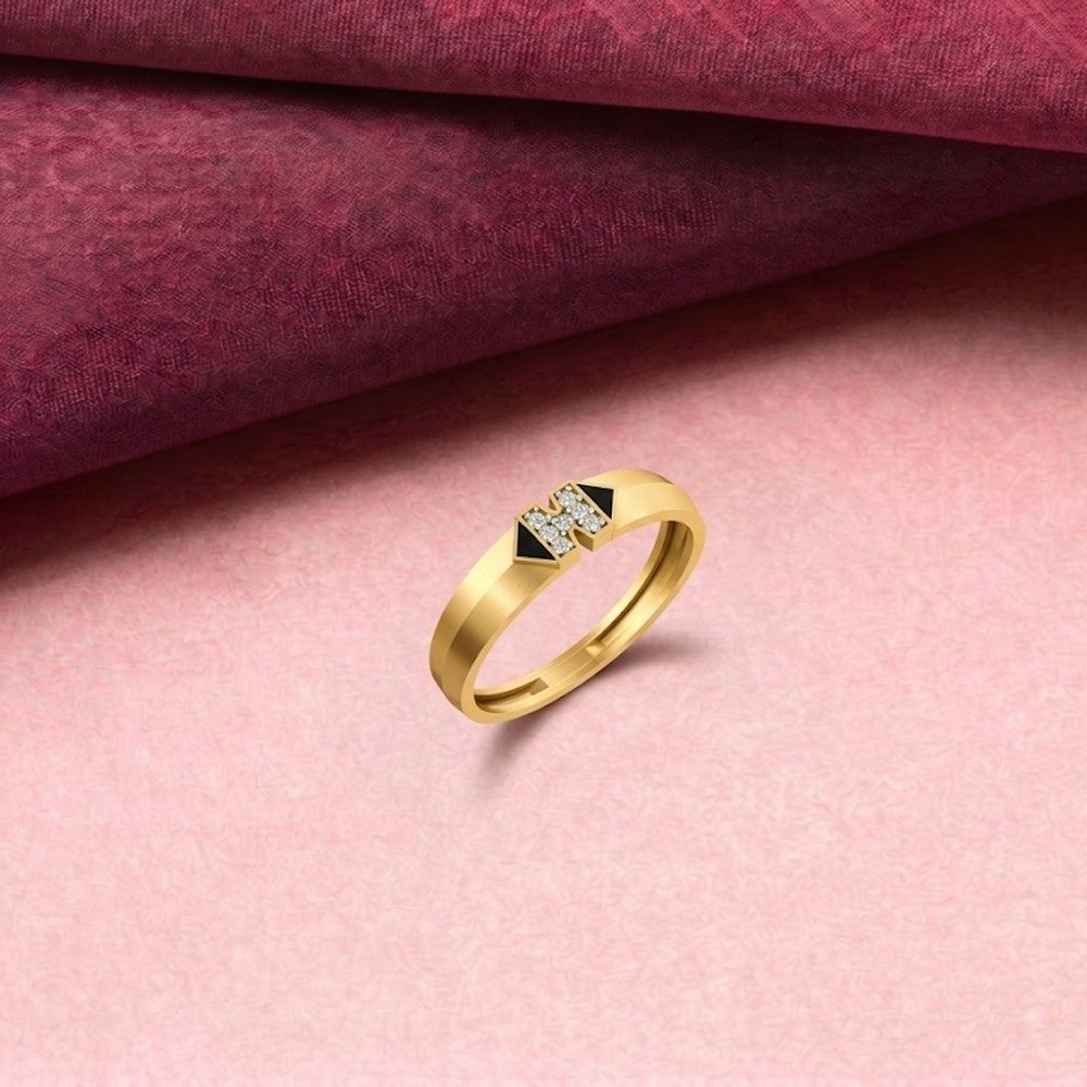 A yellow gold ring with a geometric diamond cluster, displayed on a textured pink.