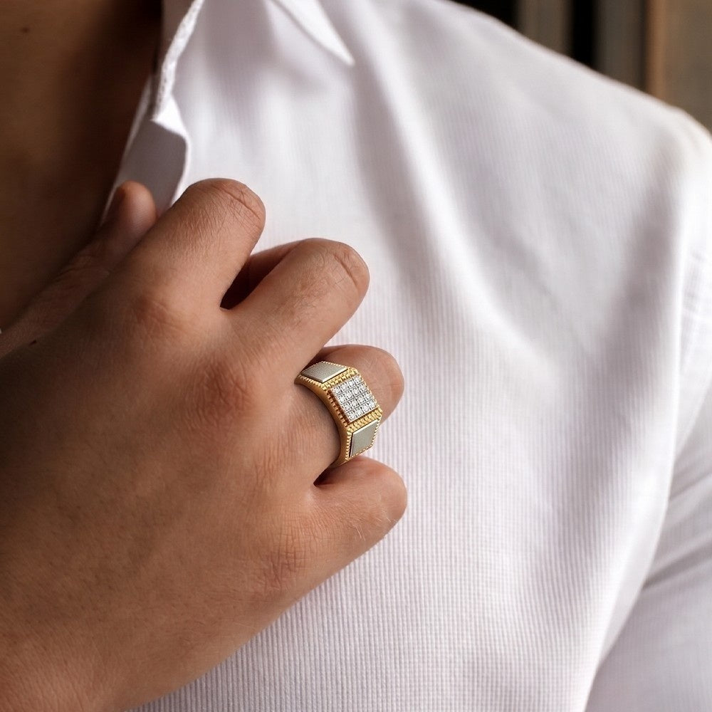 Hand wearing a gold ring with a diamond on a white shirt background