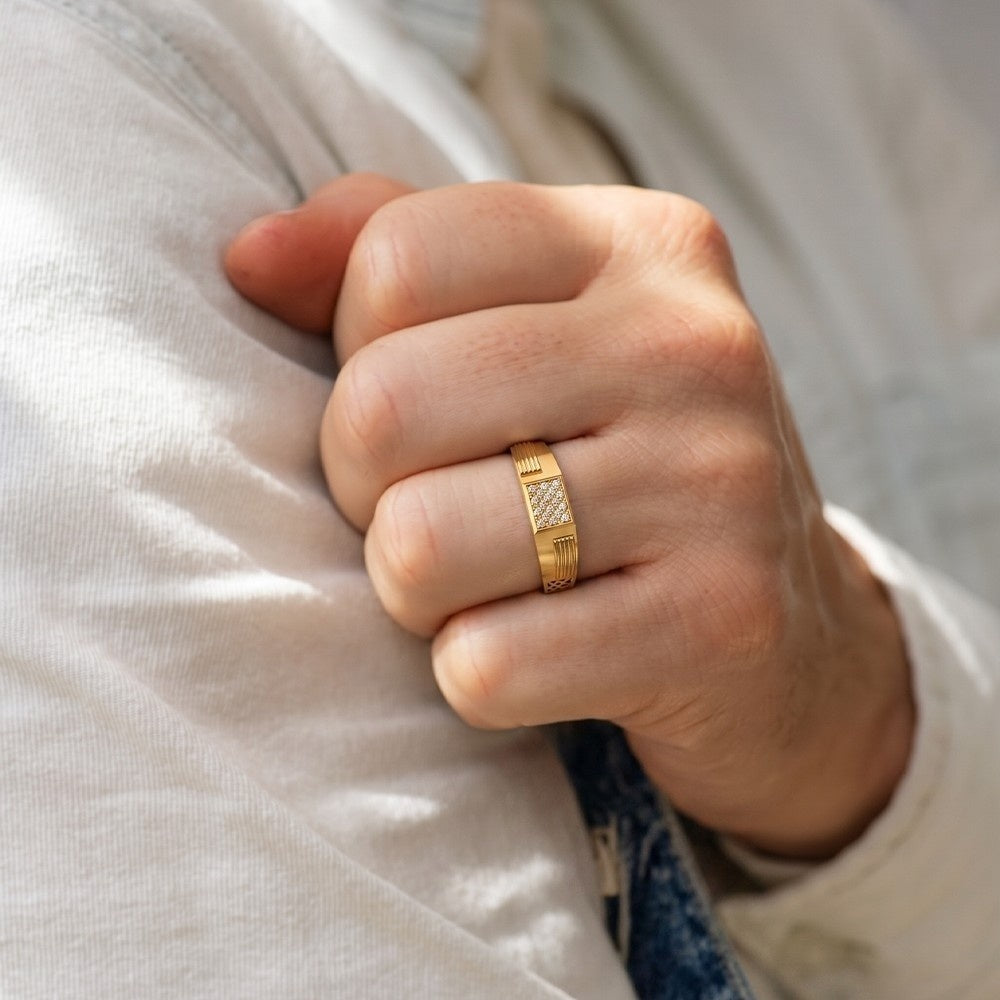 Hand wearing a gold ring on a light-colored fabric background.