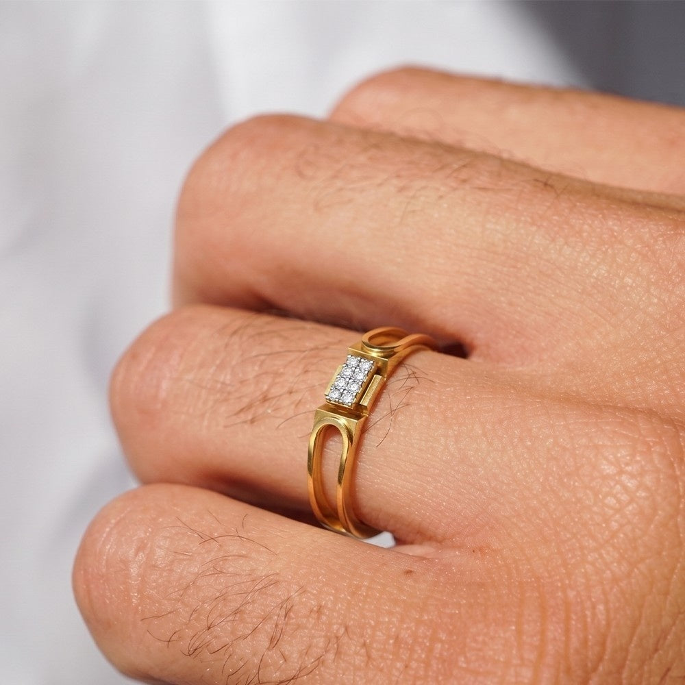 Gold ring with small diamonds on a finger against a neutral background