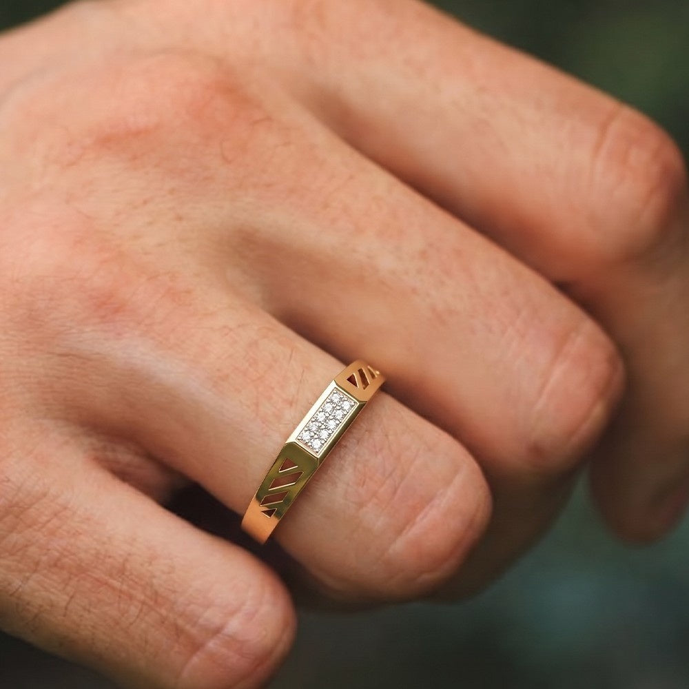 Gold ring with diamond accents on a person's finger against a blurred background.
