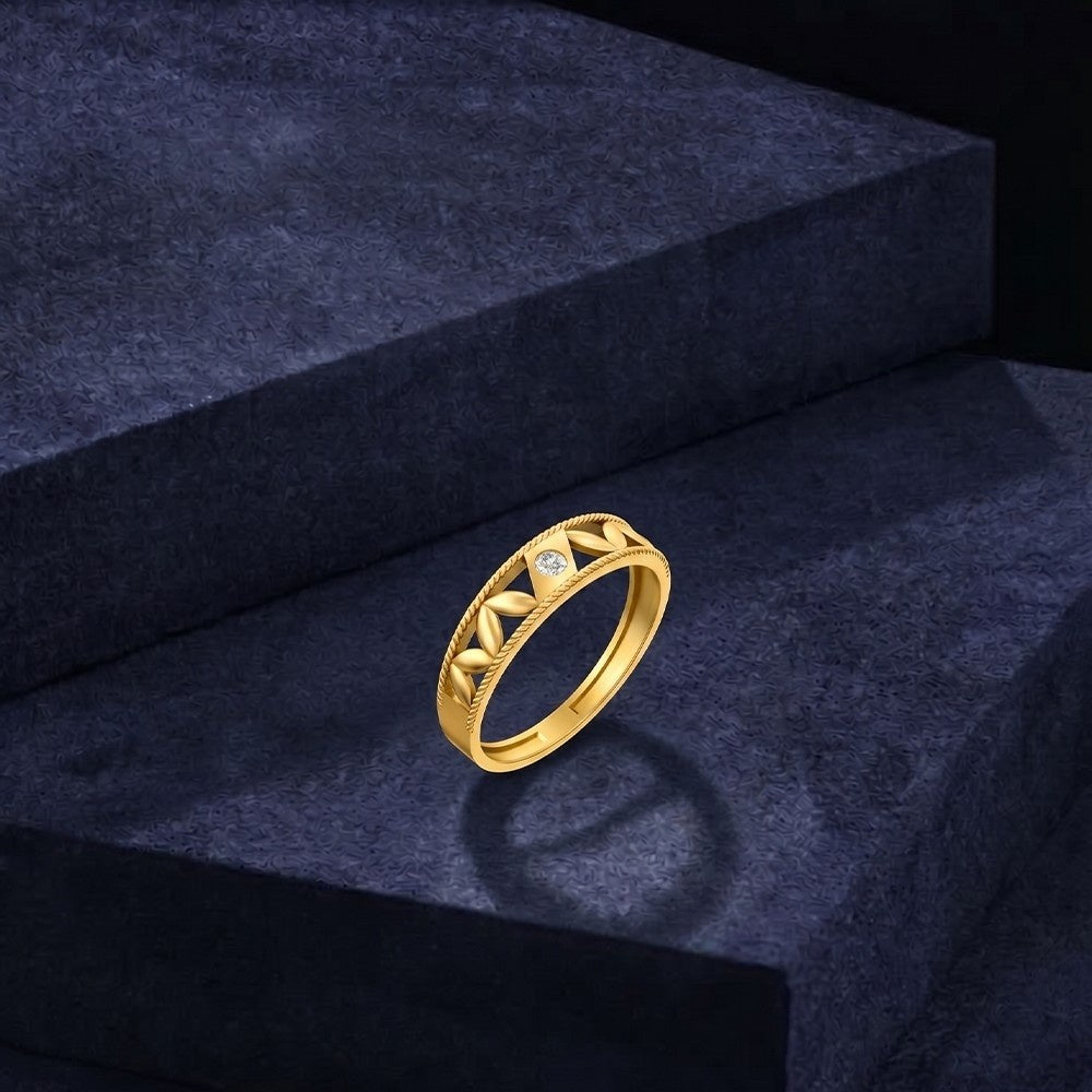 Gold ring with geometric design on a dark blue surface.