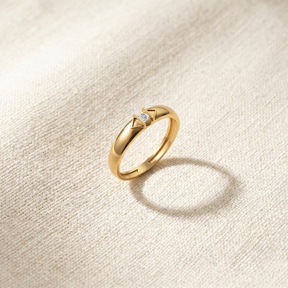 Gold ring with a diamond on a beige textured background.
