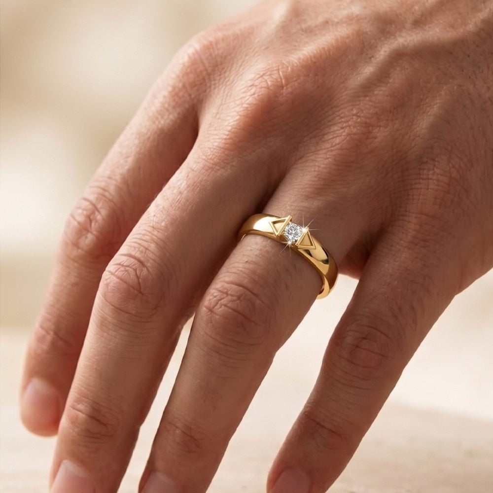 Gold ring with a diamond on a person's finger against a blurred background.