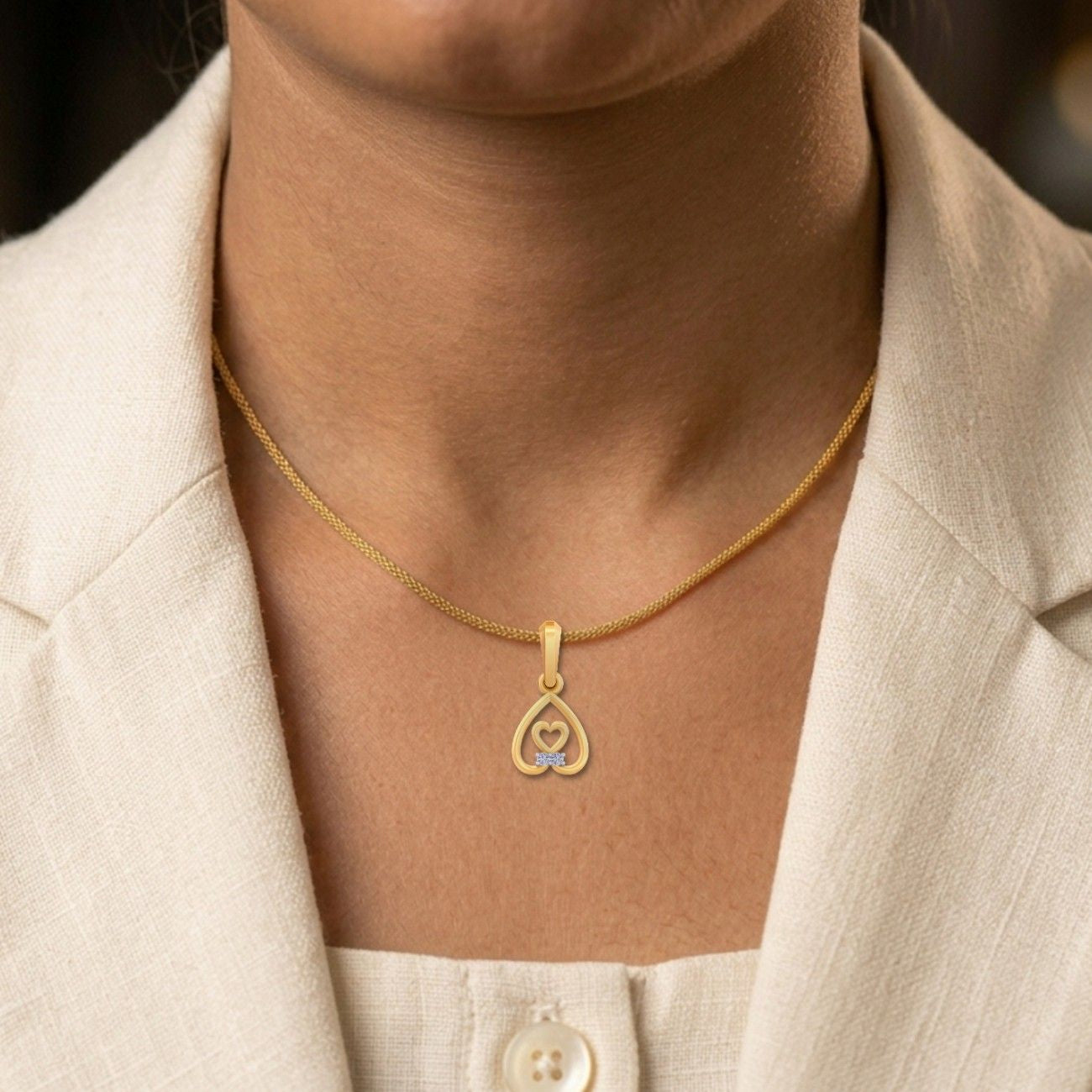 Minimalist gold heart pendant featuring a sparkling diamond detail, styled on a fine gold chain and worn with a neutral outfit.